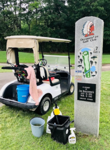 Cleaning supplies and a golf cart next to a stone monument at Occoneechee Golf Club by Stone Cold Restorations in Durham, NC.