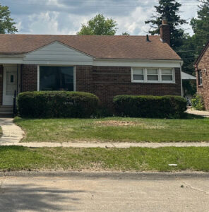 A residential front yard shows a cleared area covered in wood chips after tree removal by Magee Tree Service in Detroit, MI.