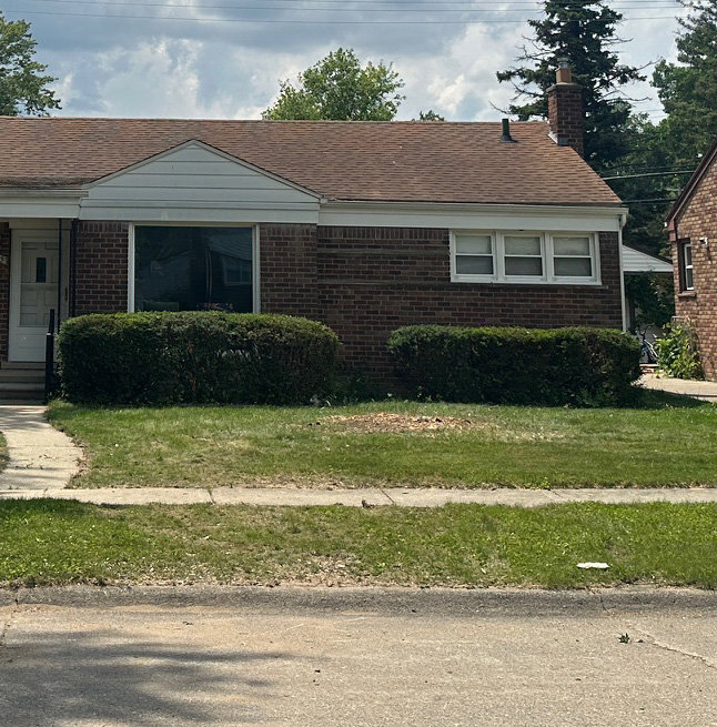 A residential front yard shows a cleared area covered in wood chips after tree removal by Magee Tree Service in Detroit, MI.