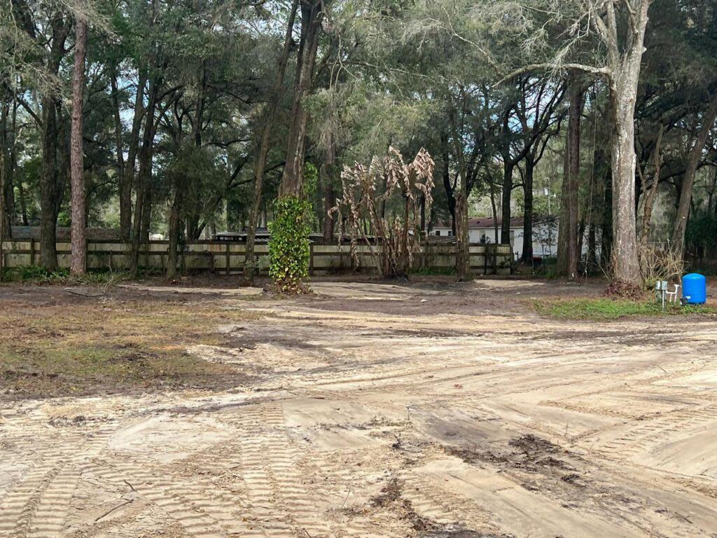 A cleared area of land adjacent to a wooden fence, showcasing site preparation services by DLT Land Management in Tampa, FL.