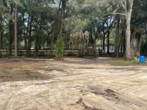A cleared area of land adjacent to a wooden fence, showcasing site preparation services by DLT Land Management in Tampa, FL.