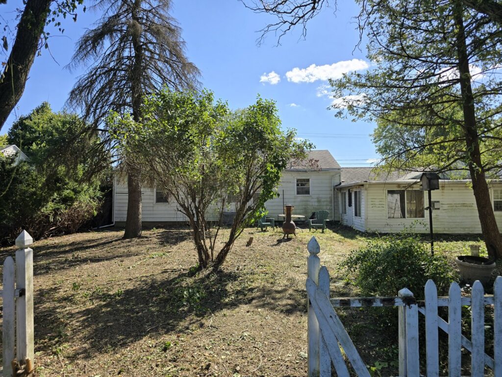 A beautifully cleared backyard with a white picket fence, showcasing the results of junk removal by JOLTZ Junk Removal in Dayton, OH.
