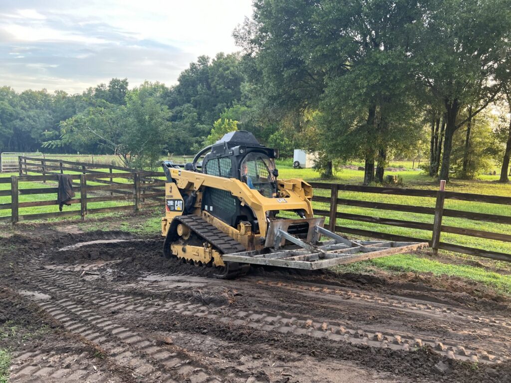 A plot of land cleared and prepared next to a small building, showcasing site work by DLT Land Management in Tampa, FL.