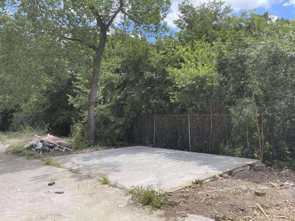 A cleared concrete slab with remaining debris around it after a demolition cleanup by Cowtown Waste Removal in Fort Worth, TX.