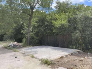 A cleared concrete slab with remaining debris around it after a demolition cleanup by Cowtown Waste Removal in Fort Worth, TX.