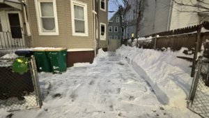 A cleared driveway and pathway between houses after snow removal by Build Brothers in Providence, RI