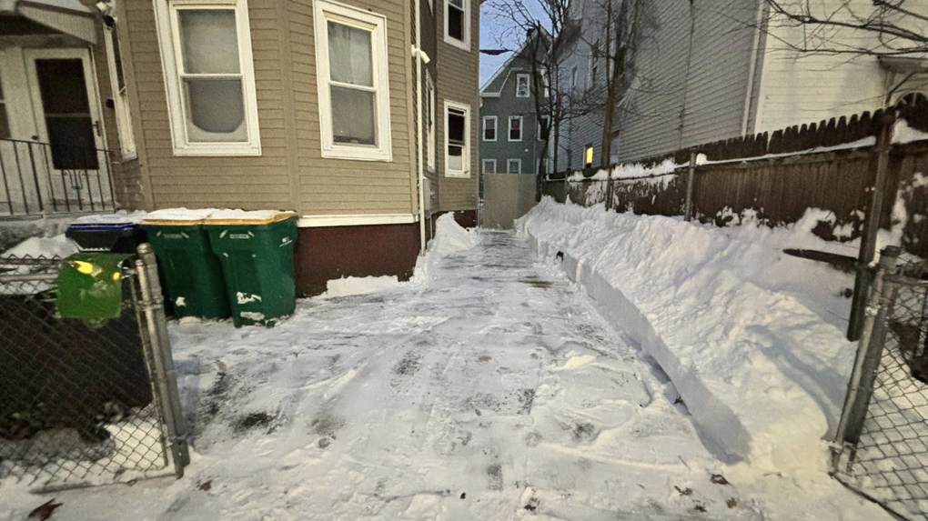 A cleared driveway and pathway between houses after snow removal by Build Brothers in Providence, RI