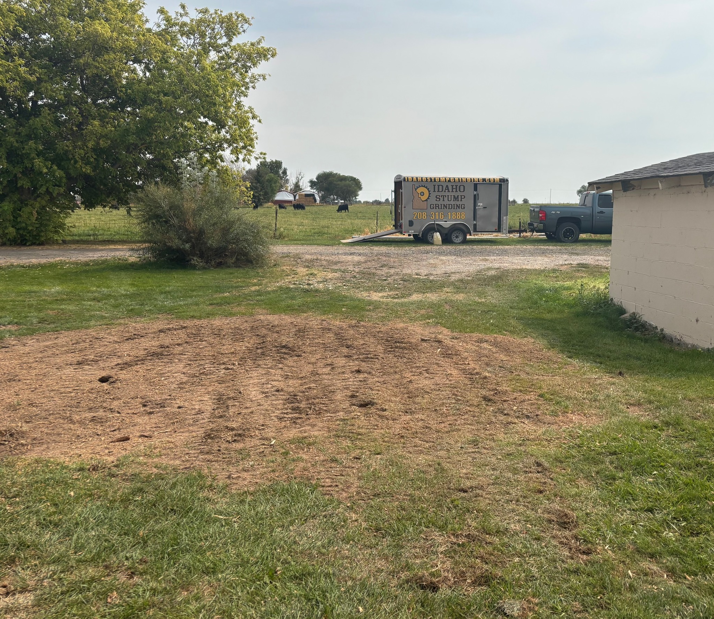 A cleared area of ground after stump removal, with the Idaho Stump Grinding trailer visible in Twin Falls, ID.