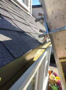 A clogged house gutter seen from a ladder, indicating a need for professional cleaning services from Schu Can Do 2-Property Services LLC in Warren, MI.