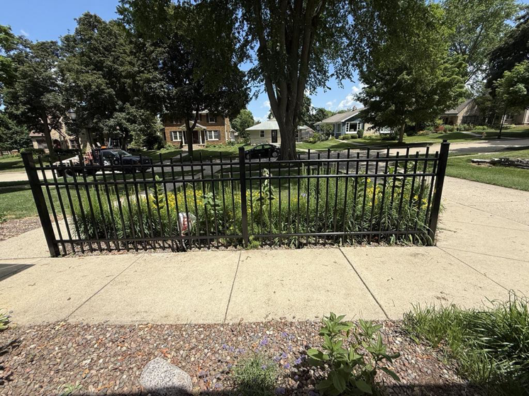 A close-up view of a black metal fence installed in a front yard by A to Z Quality Fencing and Structures-Appleton, WI.
