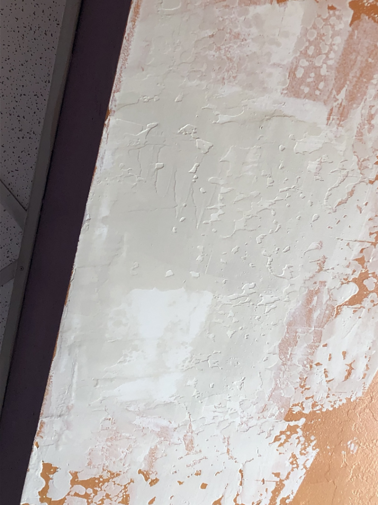 Close-up of white drywall compound applied to an orange textured wall by Fonseca's Drywall, LLC in Glendale, AZ