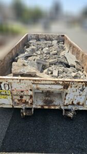 A close-up view of a roll-off dumpster filled with concrete and debris for Waste Removal and Recycling, Inc. in Sacramento, CA.