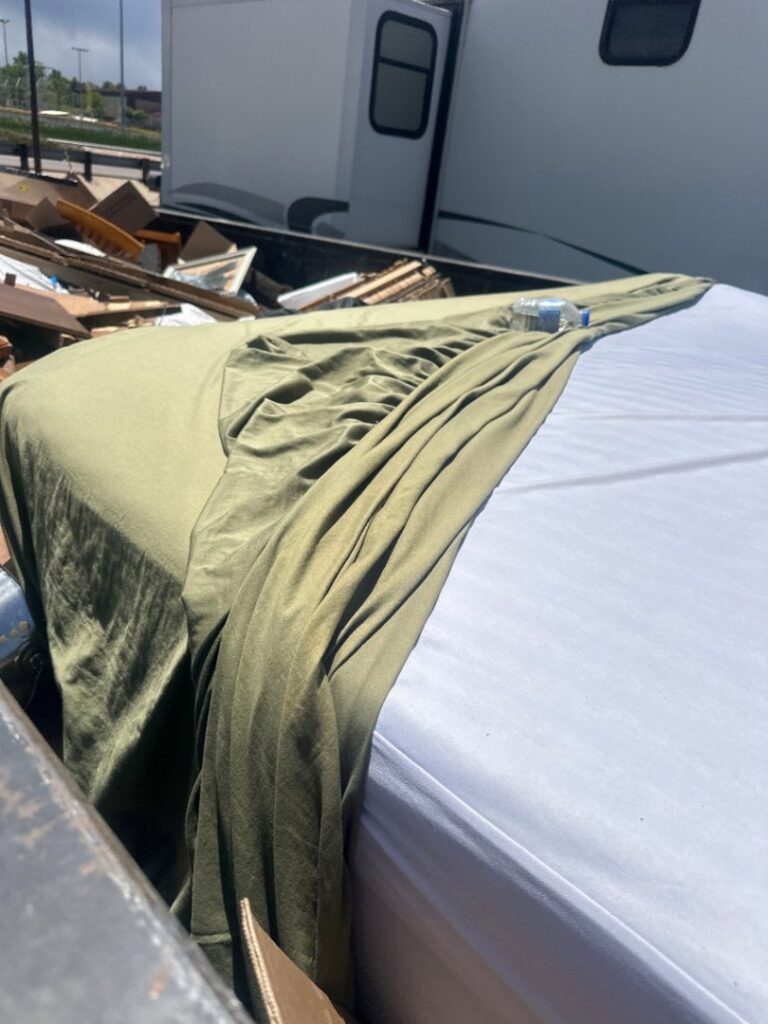 A close-up view inside a Humpty Dump Roll-Offs & Dumpsters dumpster, showing a mattress and other junk in Commerce City, CO.