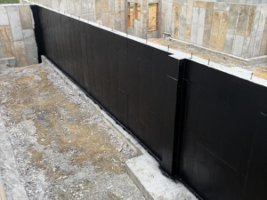 A close-up view of a foundation wall with black waterproofing membrane applied by ProSeal Waterproofing in Naugatuck, CT.