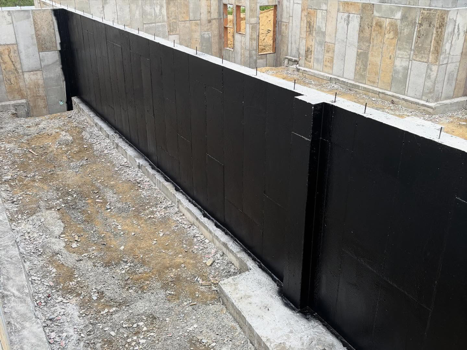 A close-up view of a foundation wall with black waterproofing membrane applied by ProSeal Waterproofing in Naugatuck, CT.