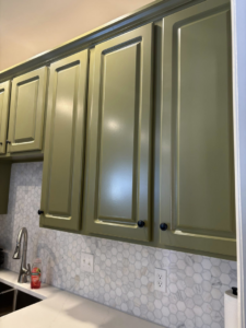 Close-up of newly painted green kitchen cabinets and a white honeycomb backsplash installed by Mauricio's Home Improvements in Raleigh, NC.