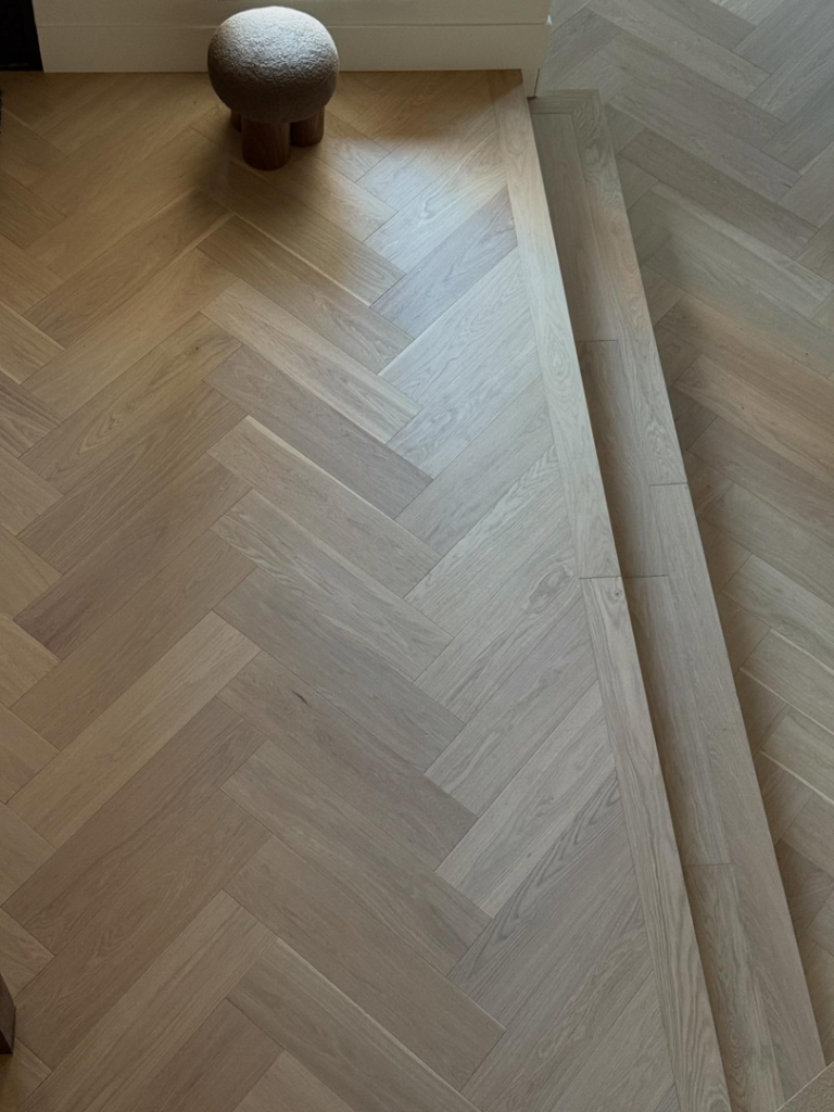 Close-up view of a newly installed herringbone pattern hardwood floor by Arizona Prestige Flooring in Surprise, AZ