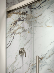A close-up of a modern shower fixture and marble-patterned wall with a glass door by Pacific Bath in Portland, OR.