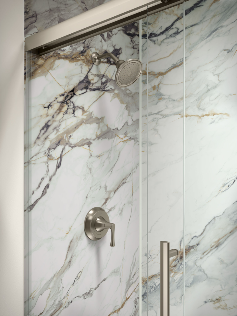 A close-up of a modern shower fixture and marble-patterned wall with a glass door by Pacific Bath in Portland, OR.