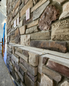 Close-up of stone veneer being installed on a wall, showing construction detail by Portland Fireplace and Chimney Inc. in Portland, OR.