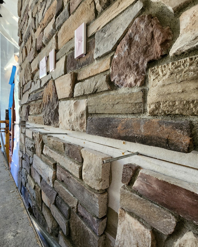 Close-up of stone veneer being installed on a wall, showing construction detail by Portland Fireplace and Chimney Inc. in Portland, OR.