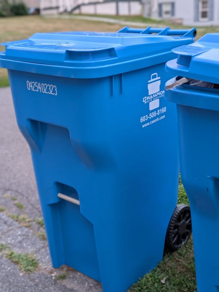A close-up of a blue residential trash and recycling bin from Champion Waste Services in Londonderry, NH.