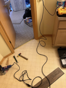 Close-up of tools and new flooring planks on an old bathroom floor by All-In-One Contracting and Home Improvement in Canton, OH