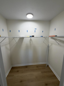 A closet with wire shelving installation in progress, marked with blue tape, by HandyWorx Home Services LLC in Kenna, WV.