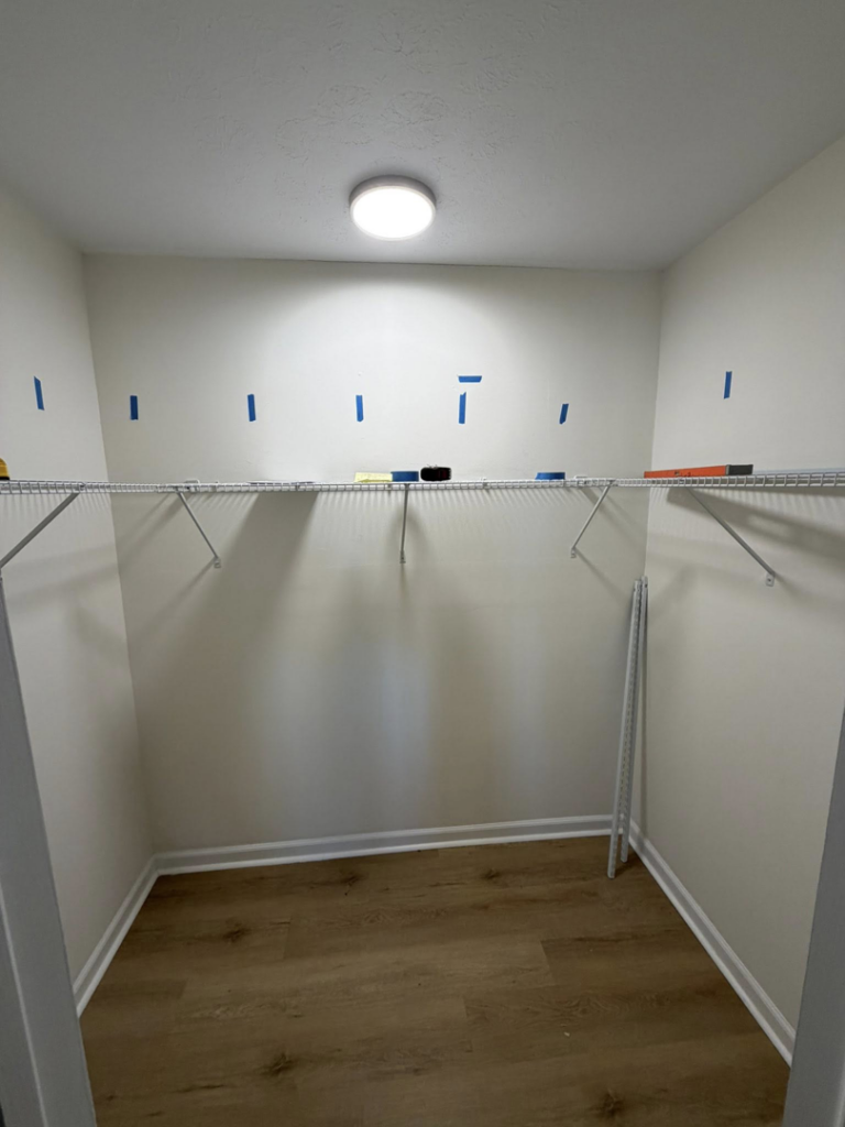 A closet with wire shelving installation in progress, marked with blue tape, by HandyWorx Home Services LLC in Kenna, WV.