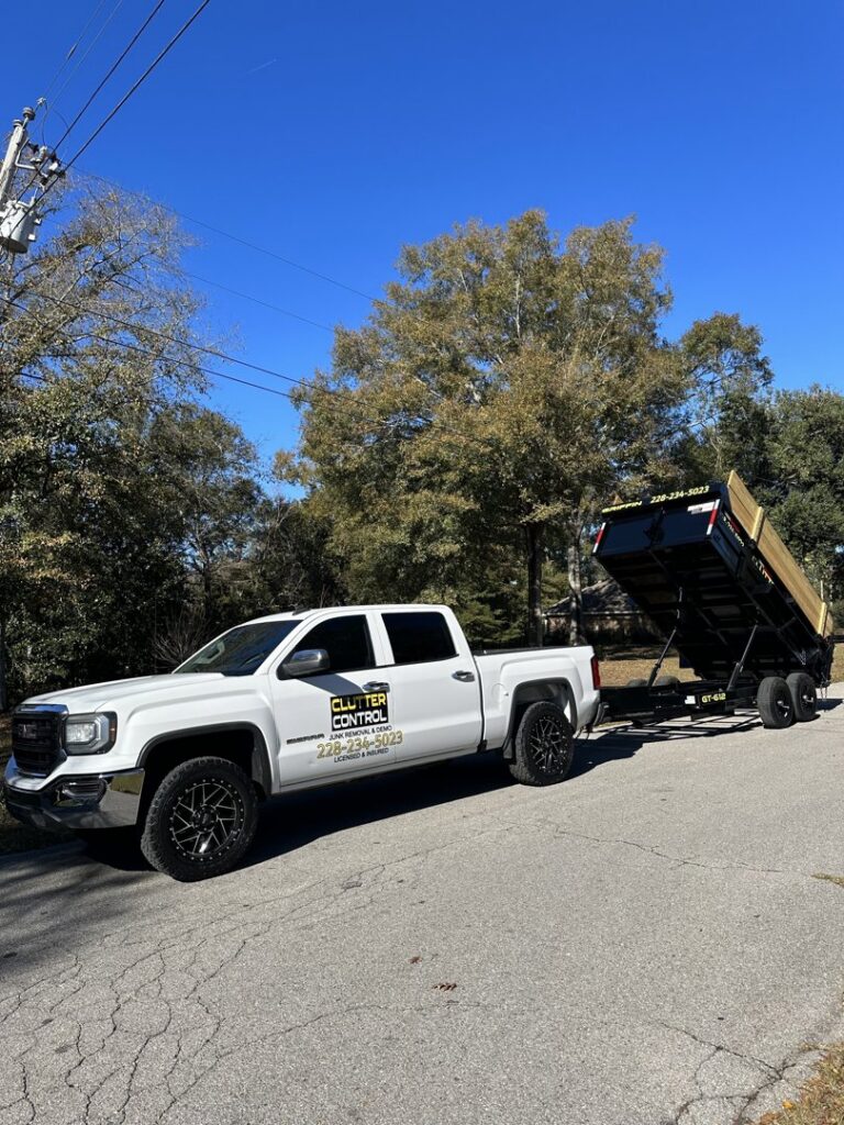 A Clutter Control Junk Removal and Demo truck with its dump trailer tilted up, showcasing equipment in Biloxi, MS.