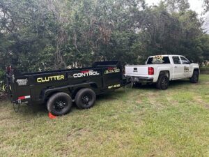 A branded Clutter Control Junk Removal and Demo pickup truck towing an empty dump trailer in Biloxi, MS, ready for a job.