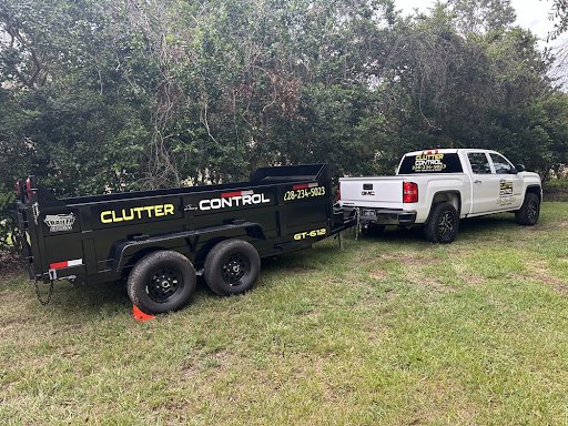 A branded Clutter Control Junk Removal and Demo pickup truck towing an empty dump trailer in Biloxi, MS, ready for a job.