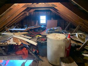 A heavily cluttered attic space filled with various items and debris, indicating a junk removal job for All Seasons Junk Removal & Dumpster Services in Center Point, IA.