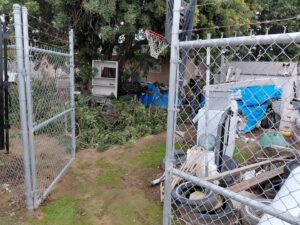 A cluttered backyard filled with branches, tarps, and general debris, indicating a property cleanup job for Valley Haul Off LLC in Visalia, CA.