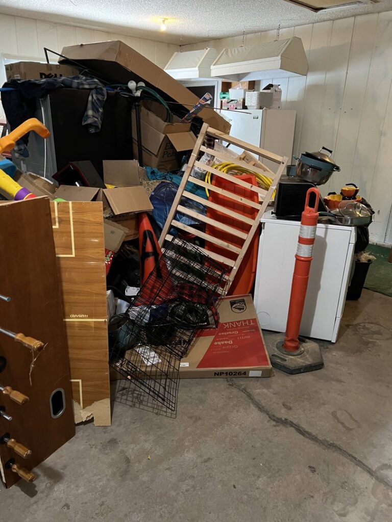 A heavily cluttered basement or storage area with boxes and appliances, showing a 'before' scene for a major cleanout by Empty It Out Junk Removal, LLC in Billings, MT.