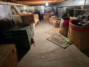 A cluttered basement filled with boxes and various items, ready for a cleanout service by T&G Dumping in Lorain, OH.