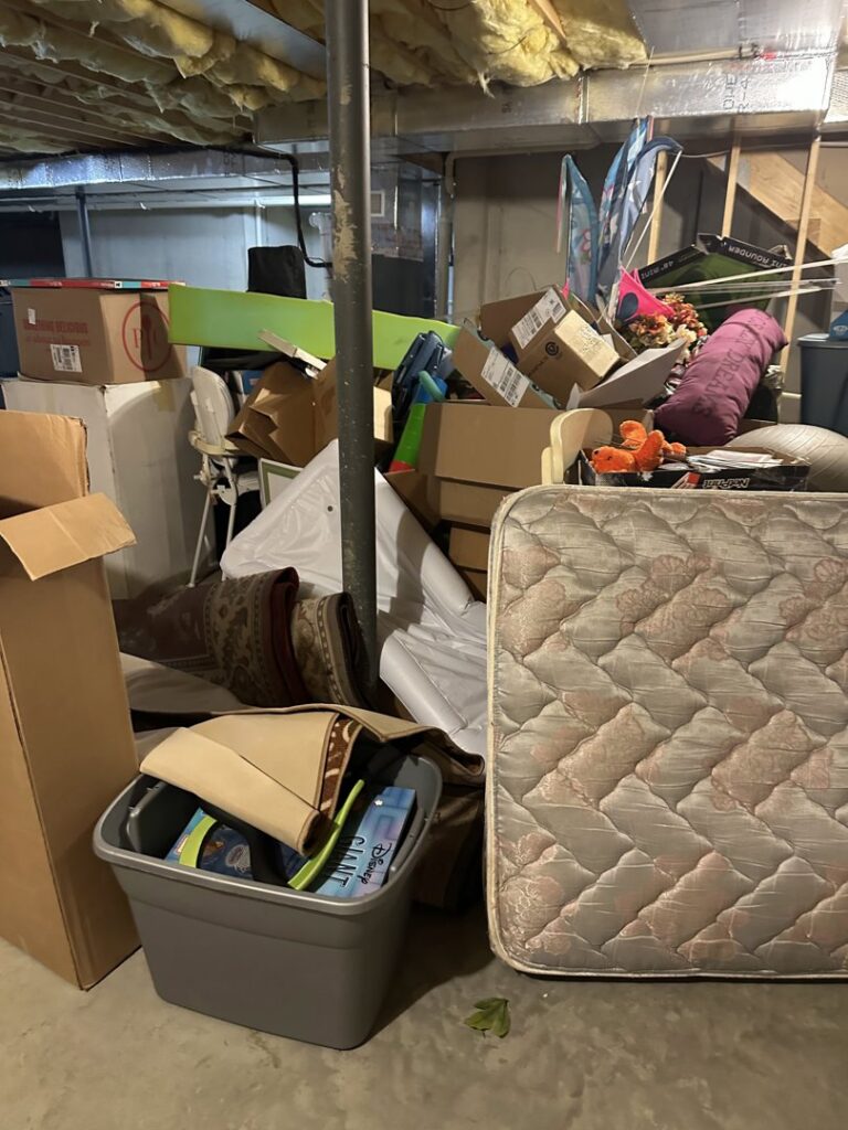 A cluttered basement filled with a mattress, boxes, and various items, ready for junk removal by Vatter Hauling Service in Lancaster, PA.