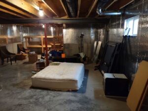 A cluttered basement filled with an old mattress, boxes, and various items, awaiting junk removal by 1-800-Declutter in Cincinnati, OH.