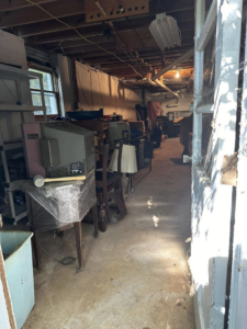 A cluttered basement filled with old electronics, furniture, and lamps, ready for junk removal by Pop's Pickup Junk & Trash Removal in Roswell, GA.
