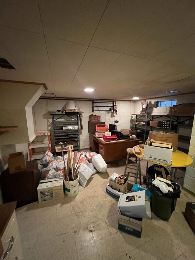 A cluttered basement room with boxes, bags, and various items ready for junk removal by Vargas Junk Removal & Dumpster Rentals in Urbandale, IA.