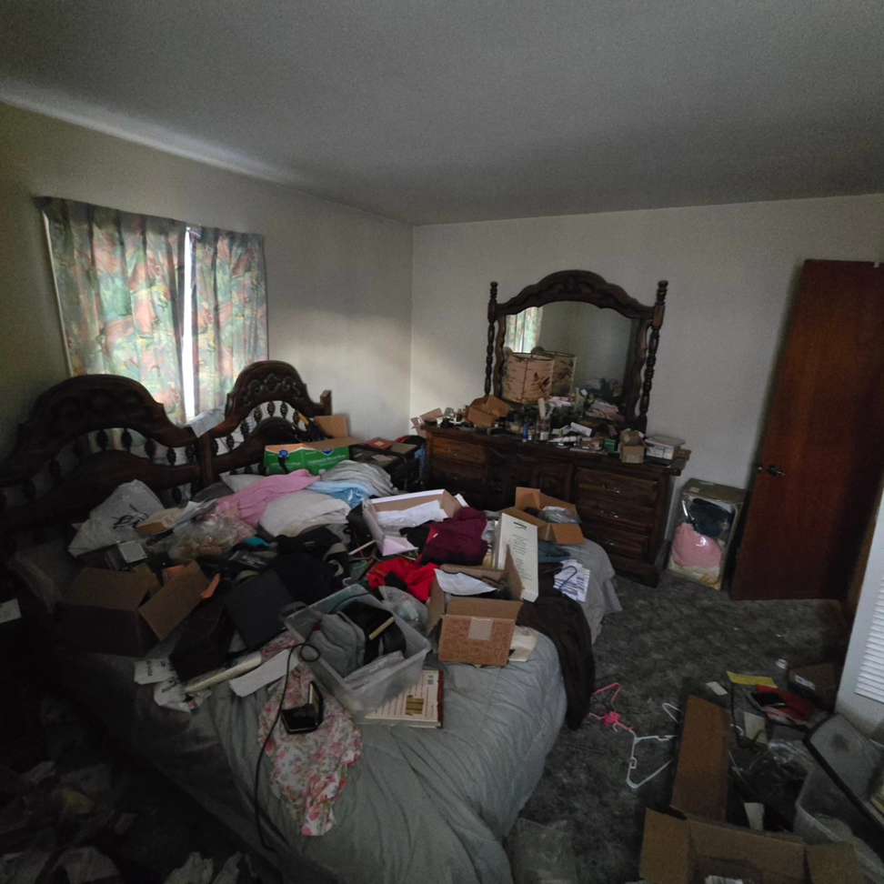 A heavily cluttered bedroom with a bed and dresser, ready for decluttering and organization by 1st State's Finest LLC, a handyman in Middletown, DE.