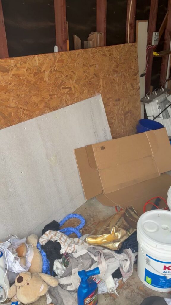 A cluttered corner of a room with clothes, boxes, and various miscellaneous junk, ready for Handymen Junk Removal in Houston, TX.