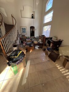 A large entryway and living area cluttered with boxes, furniture, and various items, ready for junk removal by MLG Strong Hauling & Junk Removal LLC in Henderson, NV.