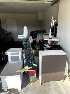 A cluttered garage filled with various household items, furniture, and boxes, representing a space before junk removal by Junk-O-Haulics in Westmoreland, TN.