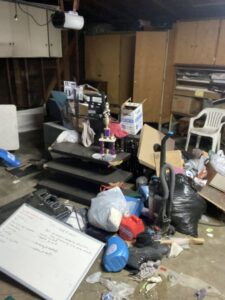 A cluttered garage floor with bags, boxes, and various items before junk removal by Larry The Rubbish Man in Los Angeles, CA.
