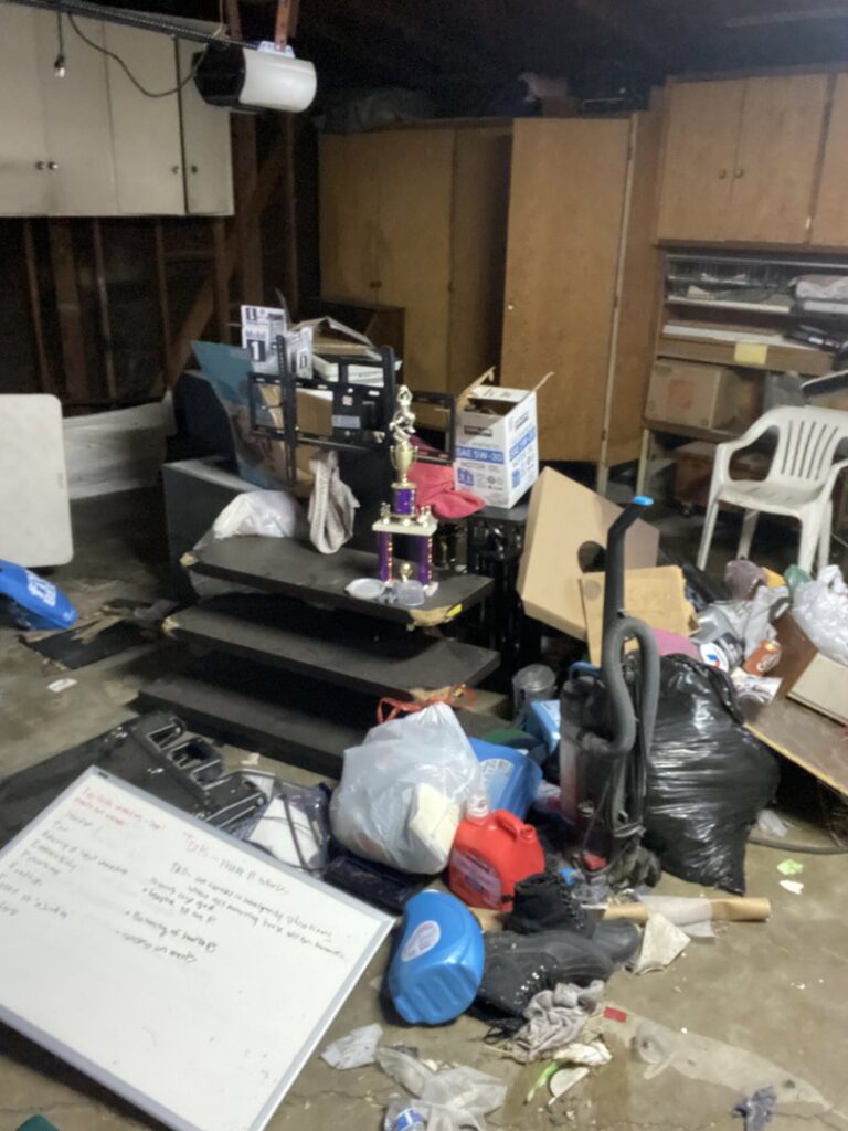 A cluttered garage floor with bags, boxes, and various items before junk removal by Larry The Rubbish Man in Los Angeles, CA.