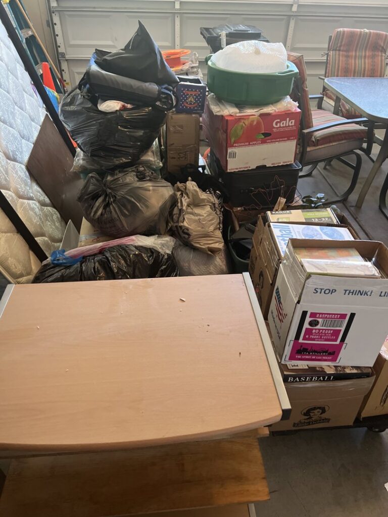 A cluttered garage filled with mattresses, boxes, and bags of trash, awaiting junk removal by Road Dogz Hauling in Las Vegas, NV.