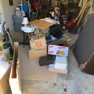 A cluttered garage filled with boxes, household items, and various junk, awaiting removal by Junk in the Truck LLC in Albuquerque, NM.