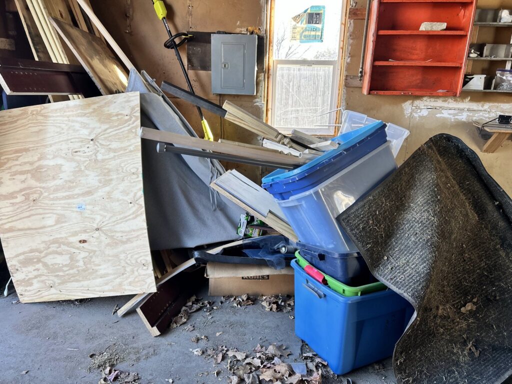 A cluttered garage filled with various items and debris, representing a space before junk removal by Sunshine junk removal LLC in Lake City, MN.