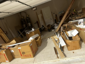 A cluttered garage filled with debris, cardboard boxes, and wood scraps, ready for junk removal by ONLY Junk Removal Services in Austin, TX.